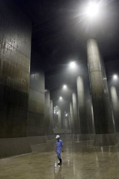 a person standing in the middle of an empty room with columns and lights on either side