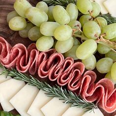 grapes, meat and cheese are arranged on a platter