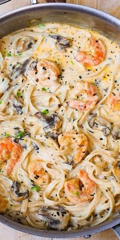 pasta with shrimp and mushrooms in a skillet on a wooden counter top, ready to be eaten