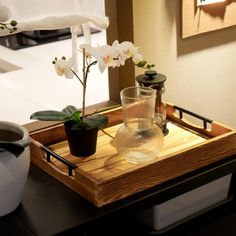 an orchid in a vase on a wooden tray