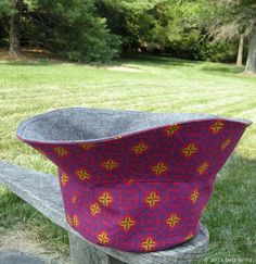 a hat sitting on top of a wooden bench in front of a grass covered field