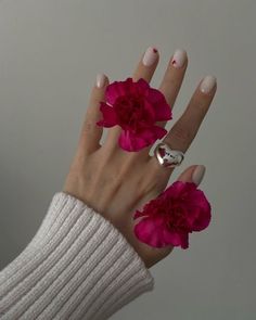 a woman's hand with pink flowers on it and two rings in the middle