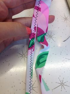 a hand is holding a pink and green ribbon on a white surface with stars in the background