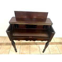 an antique wooden desk with two drawers on wheels and one drawer open to show the contents