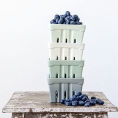 a stack of blueberries sitting on top of a table next to a white wall