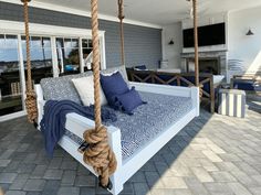 a white bed sitting on top of a wooden swing next to a brick floor covered patio