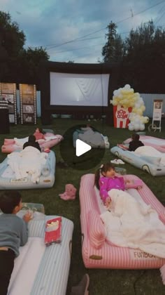 people are laying on inflatable mattresses and watching the movie at an outdoor event