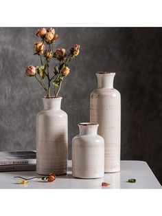 three vases with flowers in them sitting on a table