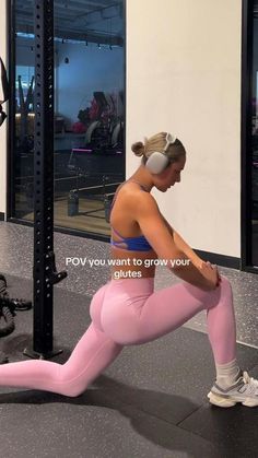 a woman in pink leggings and headphones doing squat exercises