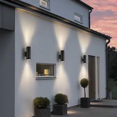 a white house with three lights on the side and two potted plants in front