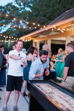 a group of people standing around a table filled with food and drinks at a party