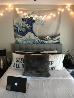 a bed with a laptop on top of it next to a wall hanging over the headboard