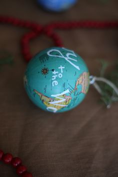 a blue ball with the word to travel on it sitting next to beads and a bead necklace