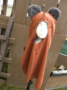 a mannequin dressed in an orange cape with fur on it's head