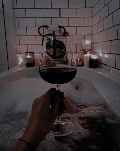 a person holding a wine glass in the bathtub