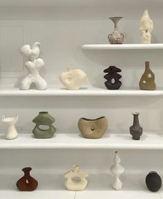 there are many different vases on the shelves in this room, including one that is white