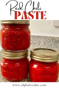 three jars filled with red chili paste sitting on top of a marble countertop next to a