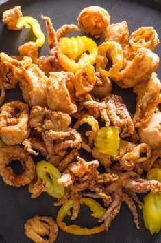 fried food on a black plate with peppers and chicken pieces in the middle, ready to be eaten