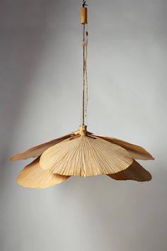 a light fixture made out of bamboo leaves hanging from a ceiling lamp with a wooden stick attached to it