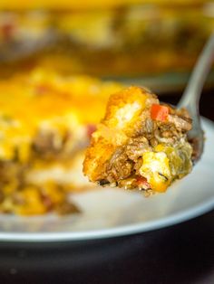 a piece of breakfast casserole on a white plate with a fork in it