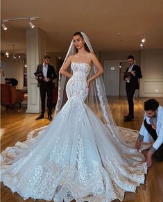 a woman in a wedding dress standing on a wooden floor