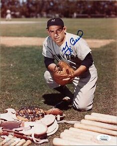 a baseball player kneeling down with his glove on the ground next to bats and balls