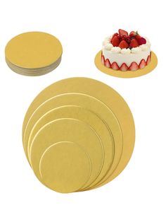 six gold plates with strawberries on top and one white cake in the middle next to it