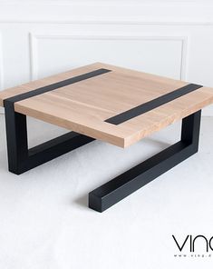 a wooden table sitting on top of a white floor next to a wall with black trim