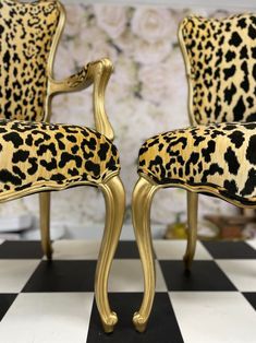 two leopard print chairs sitting on top of a black and white checkered floor