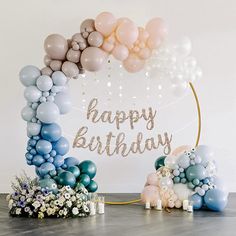 a happy birthday balloon arch with balloons and flowers on the floor next to an elephant