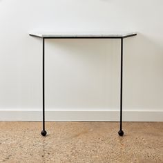 a white table sitting on top of a wooden floor next to a black metal frame