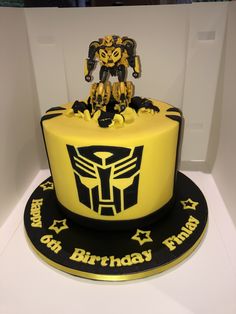 a yellow and black birthday cake with a robot on top