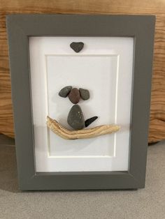 a rock and driftwood art piece in a shadow box with a heart on it