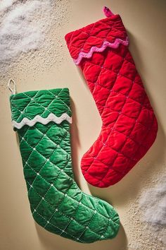 two red and green christmas stockings hanging from the wall next to each other on a white surface