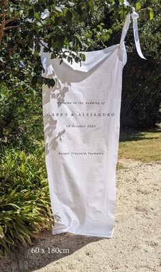 a white wedding banner hanging from a tree