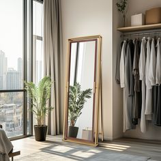 a large mirror sitting on top of a wooden floor next to a window filled with clothes