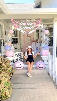 a woman sitting on the front steps of a house decorated for halloween