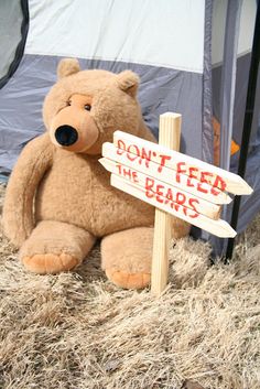 a teddy bear sitting next to a sign that says don't feed the bears