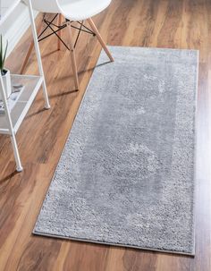 a large gray rug on top of a wooden floor next to a chair and desk