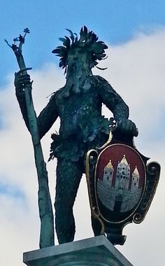 a statue on top of a building next to a street sign with a castle in the background