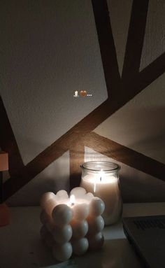 a lit candle sitting on top of a table next to a jar filled with balloons