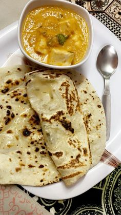 a white plate topped with two quesadillas next to a bowl of soup