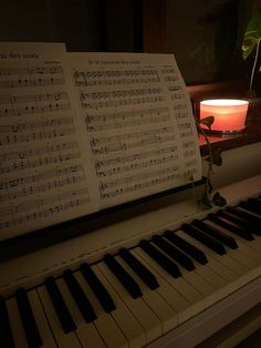 an old piano with sheet music sitting on it's stand next to a candle