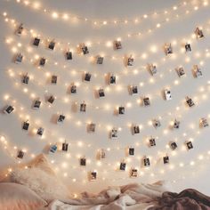 a bedroom with lights strung from the ceiling and pictures hung on the wall above it