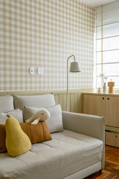 a couch with pillows on it in front of a wallpapered background and wooden floor