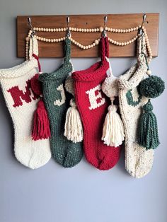 three stockings hanging on a wall with tassels and pom - poms