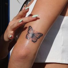 a woman's arm with a butterfly tattoo on the left side of her arm