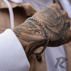 a man with tattoos on his arm wearing a chain around his wrist and holding onto a watch