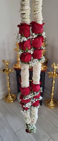 a bunch of red and white flowers are hanging from a tall tower in a room