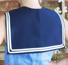 the back of a woman's blue dress with white trim